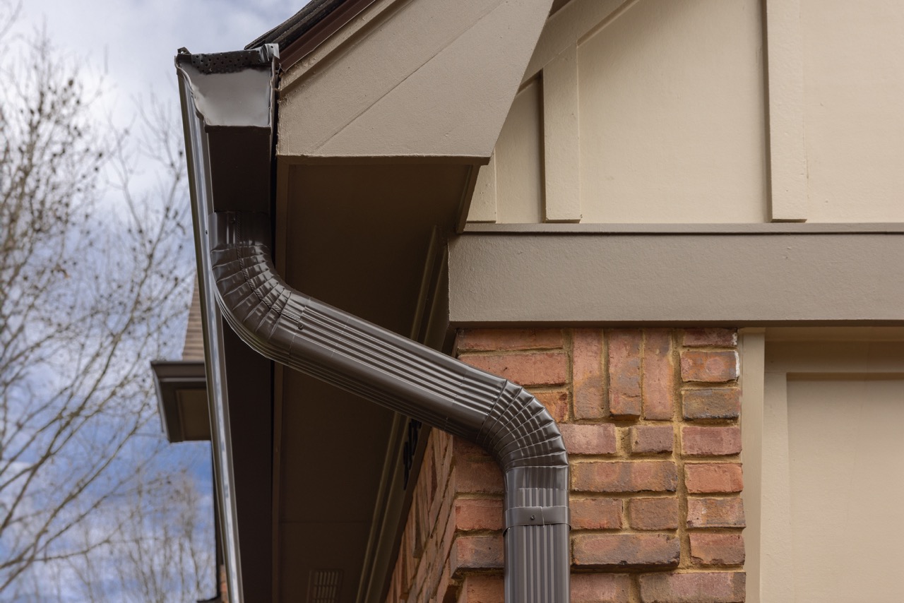 Home with tan siding, black gutters, windows and entry door | Nansemond River Roofing & Siding